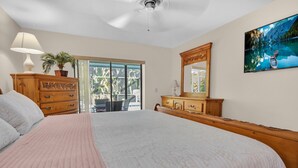 Ein Schlafzimmer mit einem großen Bett, einem Holzschrank und einer Glastür zum Balkon.