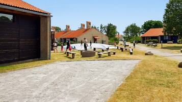 A courtyard with picnic tables, a playground, and a building with a red-tiled roof.