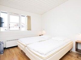 A room with two beds, a window, a heater, and a small table.