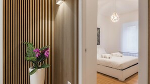 A modern bedroom with a wooden slat wall, a potted plant, a bed with white linens, and a hanging light fixture. - THE FIFTH PROPERTIES ROME (Roma)