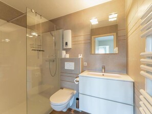 Een moderne badkamer met een douchecabine, een toilet en een wastafel met spiegel.