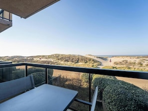 Een balkon met uitzicht op een zandstrand en duinen.