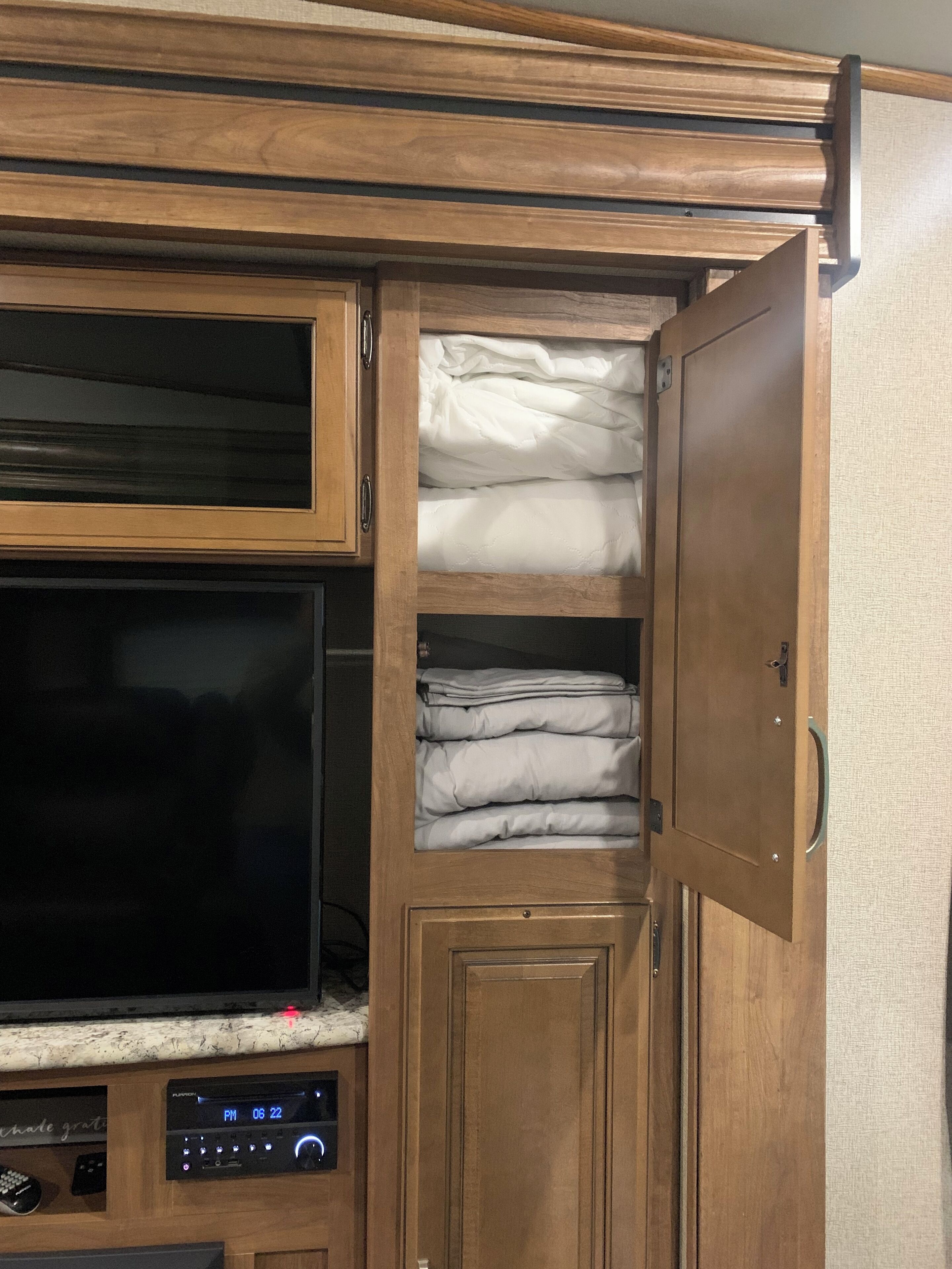 Ein kompaktes Wohnmobil-Interieur mit Fernseher, Stauraumschränken und einer Bedienkonsole.