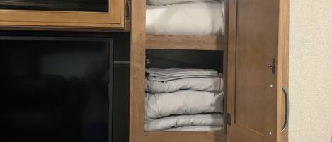 Ein kompaktes Wohnmobil-Interieur mit Fernseher, Stauraumschränken und einer Bedienkonsole.
