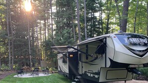 Ein Laredo Super Lite Wohnmobil auf einer Rasenfläche mit einer Terrasse und Sitzgelegenheiten im Freien.