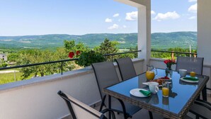 Un balcón con mesa dispuesta para el desayuno, con vistas a un paisaje pintoresco.