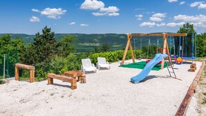 Un parque infantil con columpios, tobogán y bancos.
