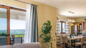Una sala de estar moderna con un sofá, comedor y vistas al exterior.