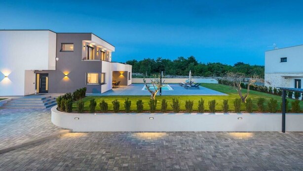 Una moderna casa a due piani con piscina, prato curato e vialetto lastricato.