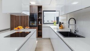Una cucina moderna con mobili bianchi, un lavello nero e un forno integrato.