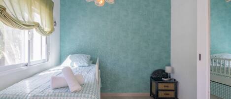 A bedroom with a bed, a nightstand, a wall-mounted air conditioner, and a window with curtains.