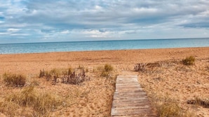 A sandy beach with a wooden pathway leading to the water.