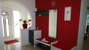 Une salle de bain avec un mur rouge, un lavabo blanc, un miroir et une plante en pot.