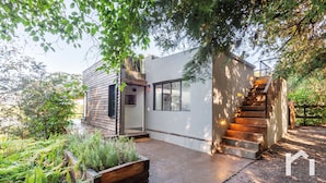 A modern house with a wooden exterior, a concrete staircase, and a garden with ferns. - Casita Panadería Cozy House in San Simón (Valle de Bravo)