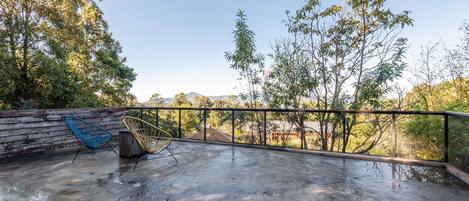 A balcony with a concrete floor, two chairs, and a wooden wall.