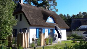 A traditional house with a thatched roof, white walls, and blue shutters. - Wave Rider Comfortable Holiday Residence (Glowe)