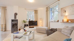 A modern living room with a fireplace, a flat-screen TV, a sofa, and a coffee table. - Wave Rider Comfortable Holiday Residence (Glowe)