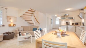 A modern apartment with a dining area, kitchen, and living space. - Wave Rider Comfortable Holiday Residence (Glowe)