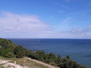 Un paysage côtier offrant une vue dégagée sur la mer, un sentier pédestre et quelques zones verdoyantes.