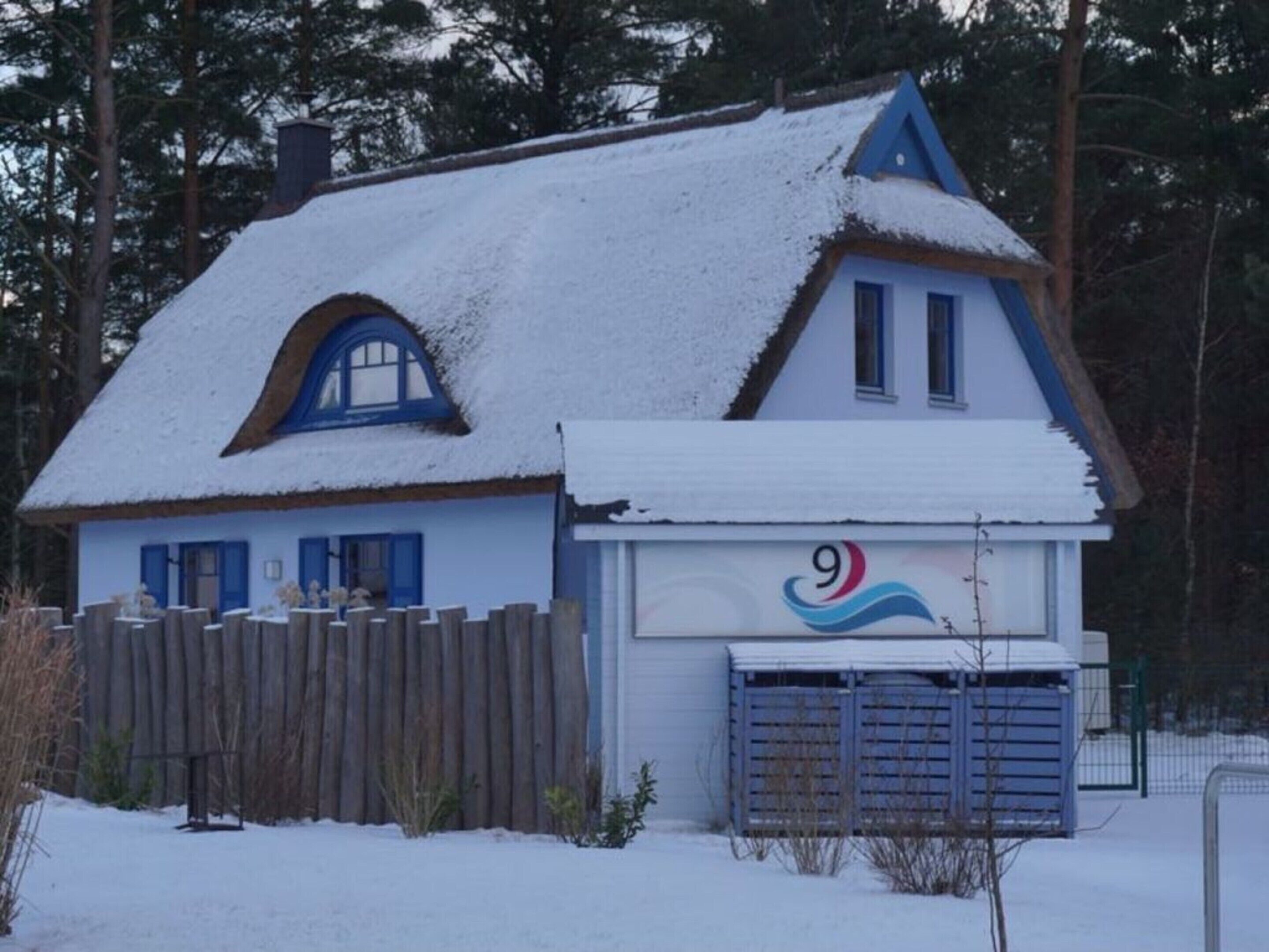 A snow-covered house with a blue roof and a number 9 sign on the garage door.