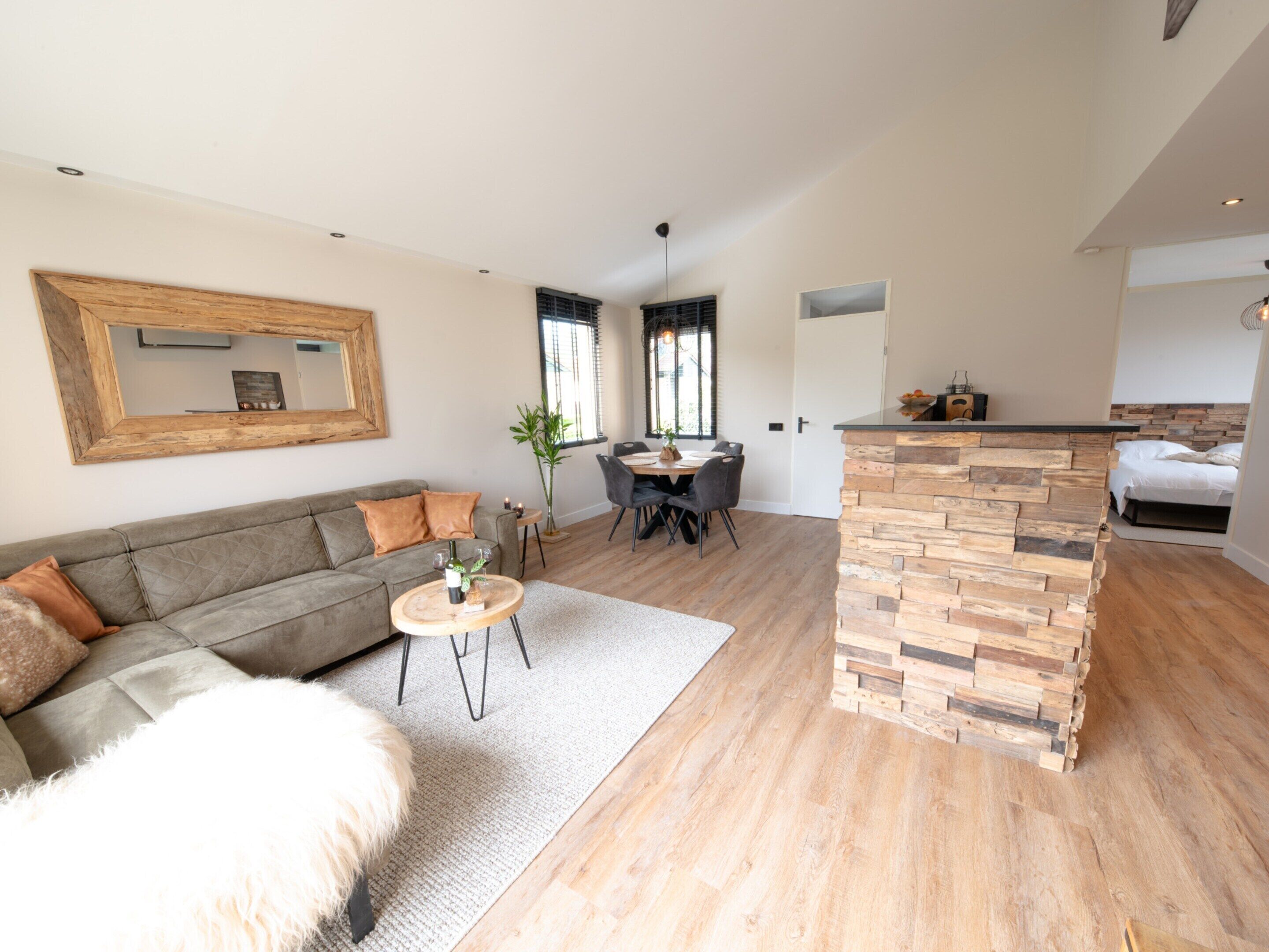 A modern living room with a sofa, a dining table, and a kitchen area with a stone counter.
