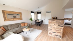 A modern living room with a sofa, a dining table, and a kitchen area with a stone counter. - Holiday Home in Zevenhuizen With Sauna (Zevenhuizen)