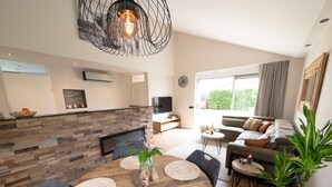 A modern living room with a wooden dining table, a sofa, and a TV. - Holiday Home in Zevenhuizen With Sauna (Zevenhuizen)