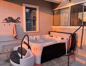 A hot tub with a ladder, a towel rack, and a window with blinds.