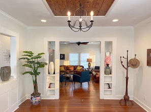 A hallway leading to a living room with a ceiling fan, a chandelier, and a potted plant. - 7 bedroom luxury, hot tub, porch, near downtown (San Antonio)