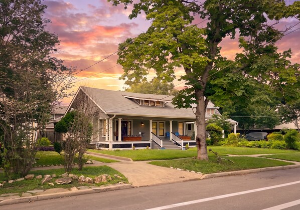 A two-story house with a porch, a front yard with a lawn, and a street view.