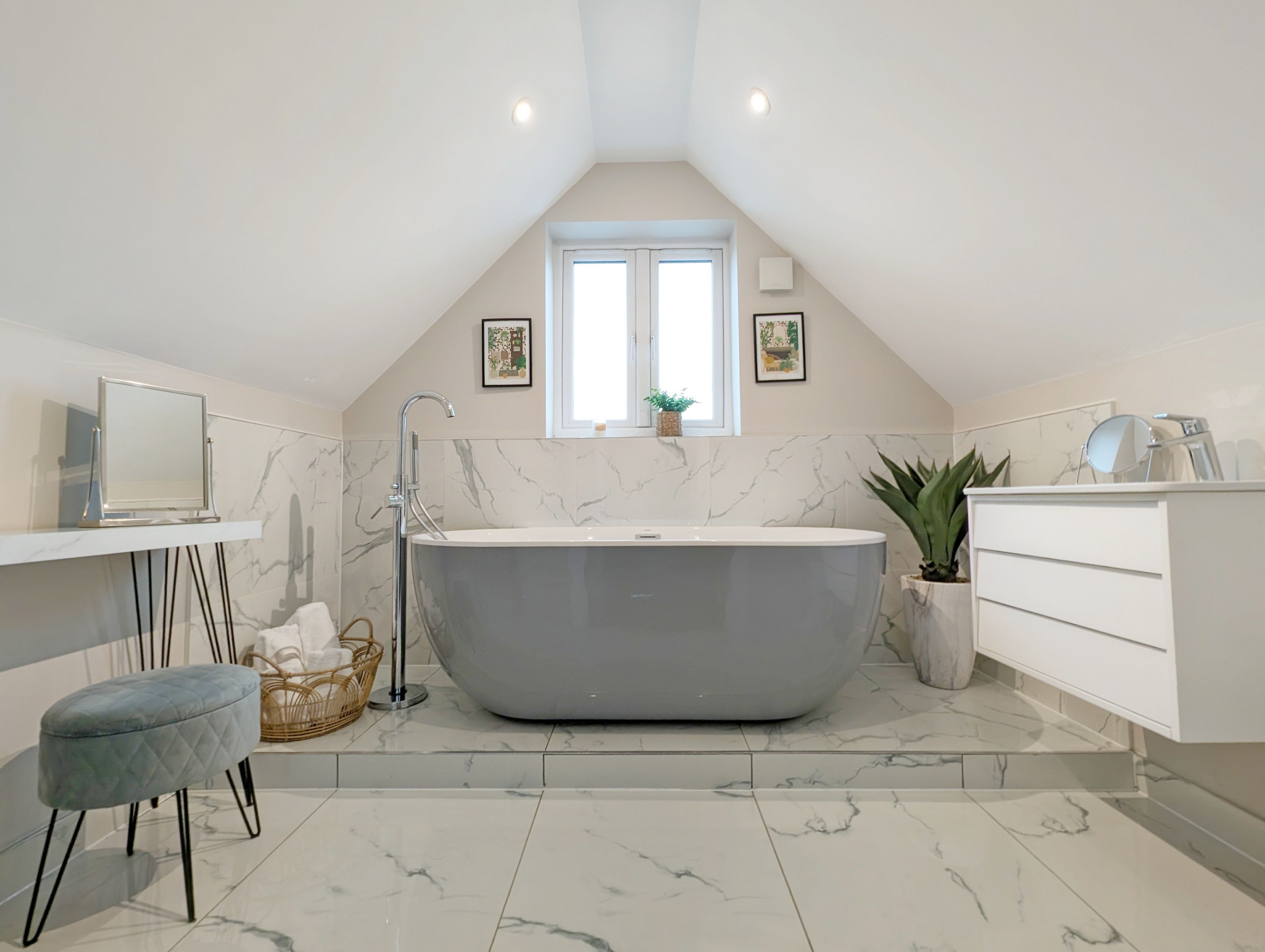 A modern bathroom with a freestanding bathtub, a vanity with a mirror, and a small stool.