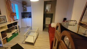 Een knus woongedeelte met een kitchenette, een eethoek en een rode bank.