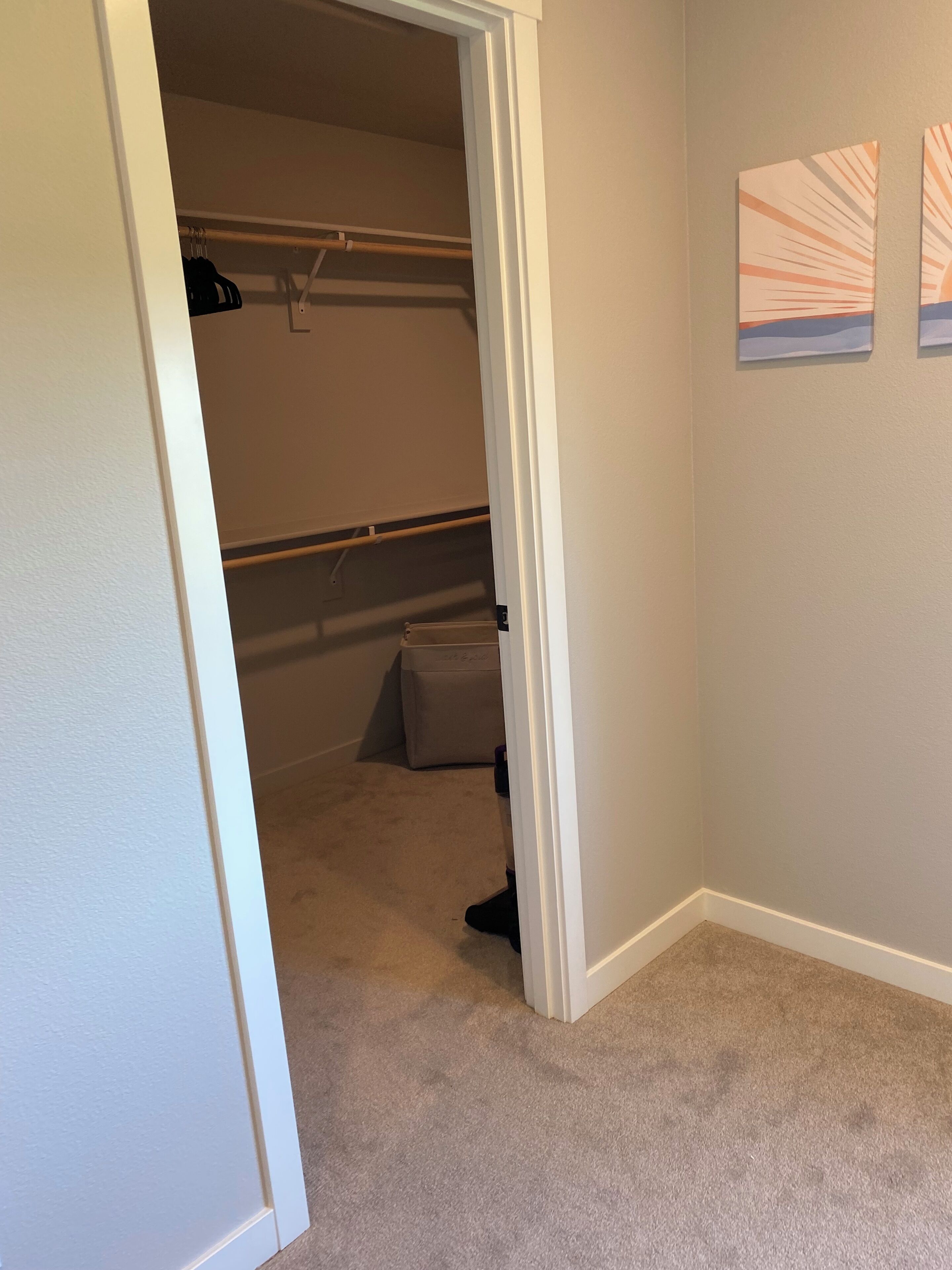 A walk-in closet with hanging space and a storage bench.