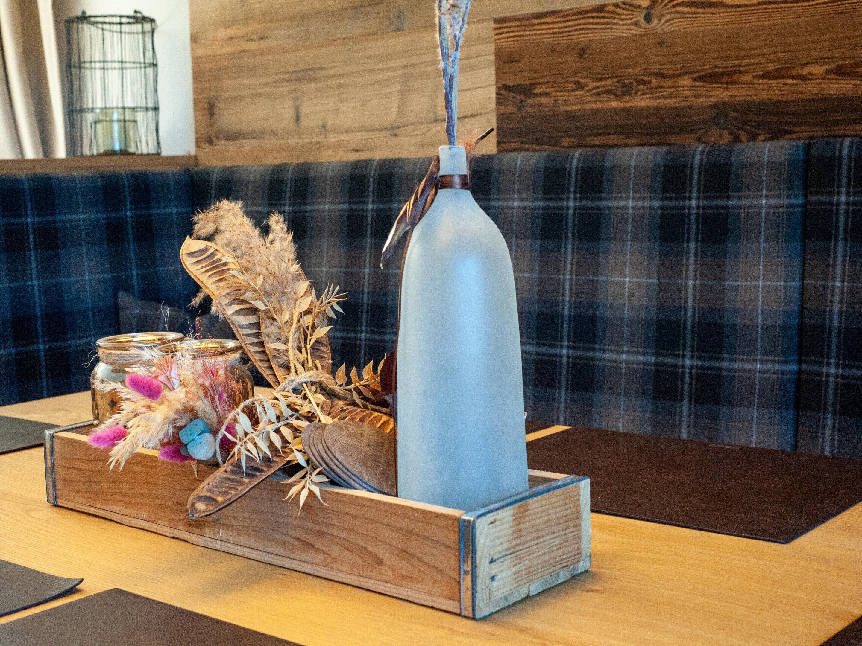 A wooden table with a glass bottle, a jar with decorative items, and a woven basket.