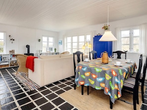 A cozy living room with a sofa, a dining table with chairs, a fireplace, and a large window.