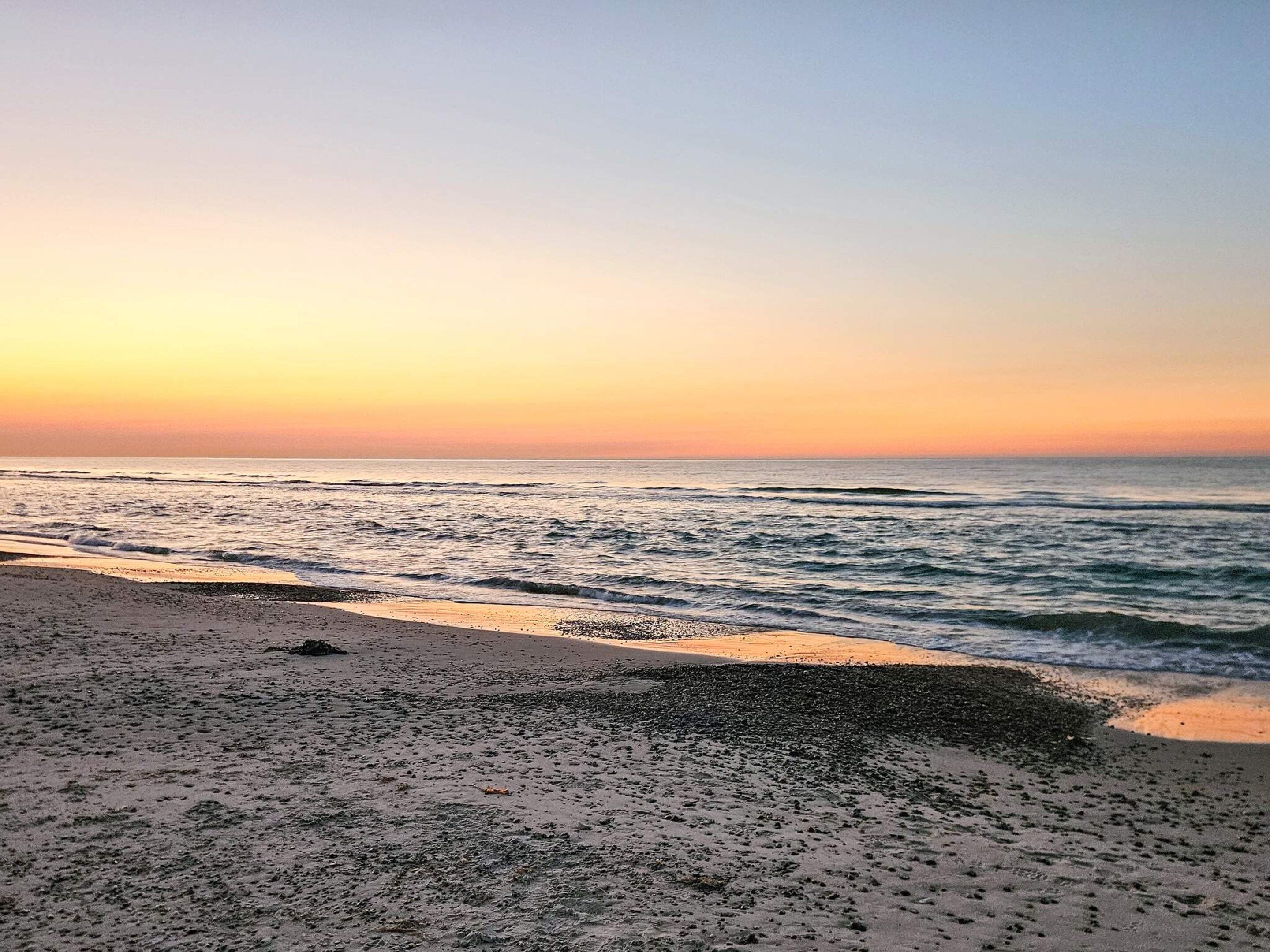 Une plage avec des vagues au coucher du soleil.
