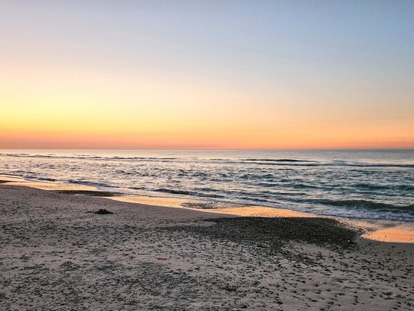 A beach with waves at sunset.