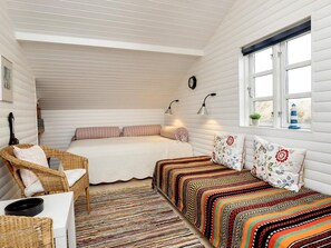 A cozy room with a bed, a wicker chair, a colorful rug, and a window with a view. - 5 Person Holiday Home in Brovst (Brovst)