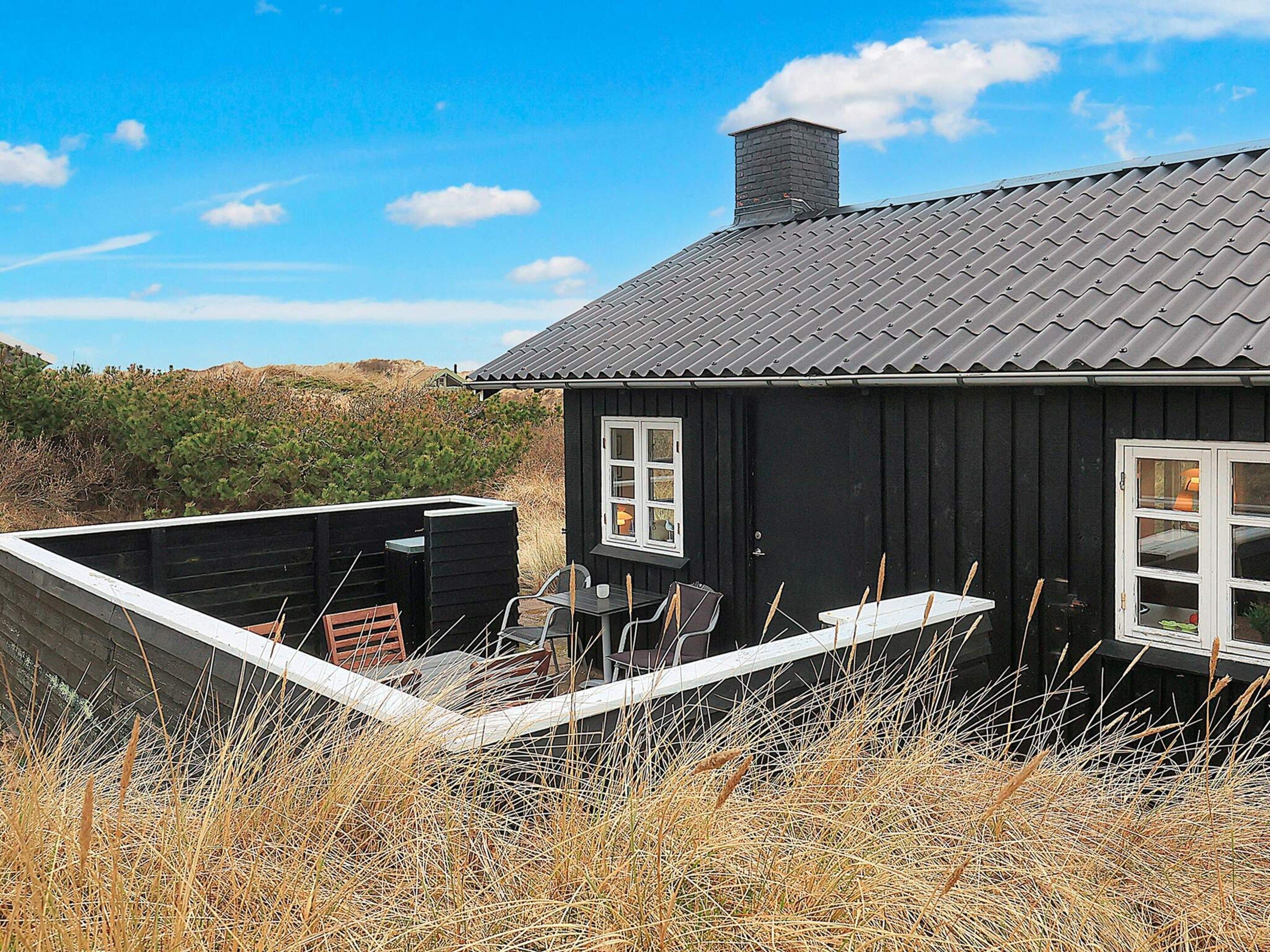 Et sort hus med et gråt tag, et vindue og en dør.