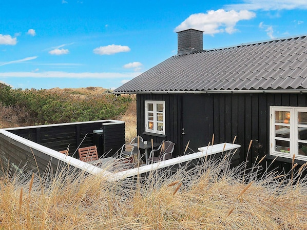 A black house with a grey roof, a window, and a door.