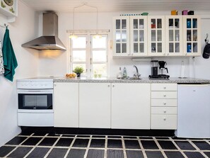 A kitchen with white cabinets, a stove, a sink, and a coffee maker.