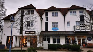 A multi-story building with a sign for 'Marc O'Polo' and 'Wetterfest' on the facade. - Message in a Bottle Modern Retreat (Zingst)