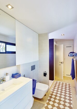 A modern bathroom with a large mirror, white tiles, a white sink, and a toilet. - Luxurious Ocean Front Holiday Home (San Bartolomé de Tirajana)