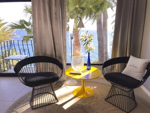 A room with two black wire-framed chairs, a yellow round table, and a view of the sea through large windows. - Luxurious Ocean Front Holiday Home (San Bartolomé de Tirajana)
