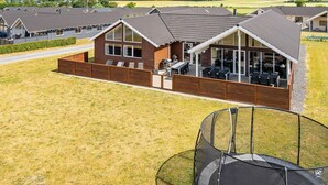 A residential area with multiple houses, a grassy lawn, and a trampoline. - 5 Star Holiday Home in Bogense (Bogense)