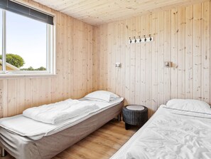 A room with two single beds, a window, and a wall-mounted light fixture.