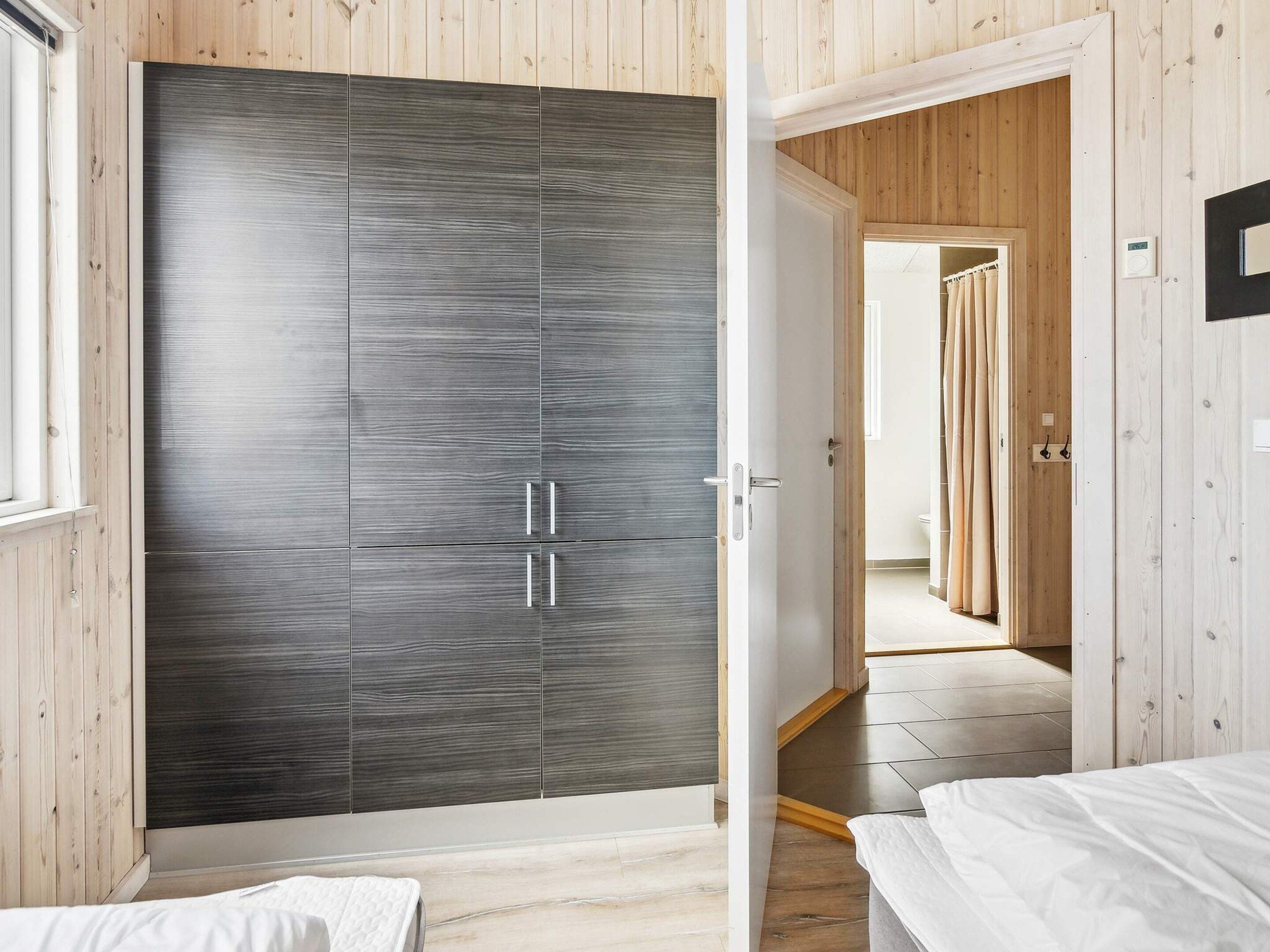 Un dormitorio con un armario, una cama y suelo de madera.