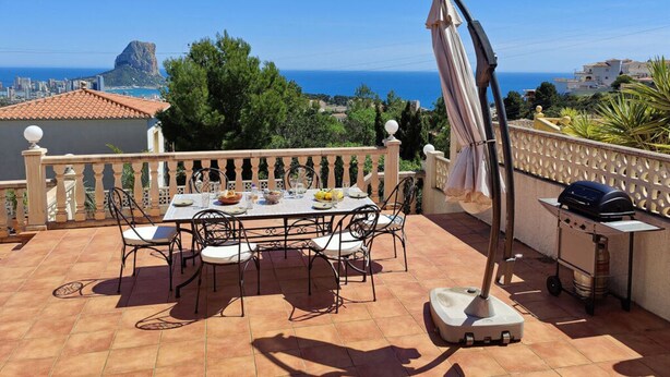 A terrace with a table and chairs, a grill, and a view of the sea and cityscape. - Villa Fiorida Comfortable Holiday Residence (Calpe)