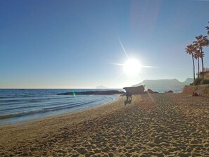 A beach with a boat on the sand, palm trees, and a clear sky. - Villa Fiorida Comfortable Holiday Residence (Calpe)