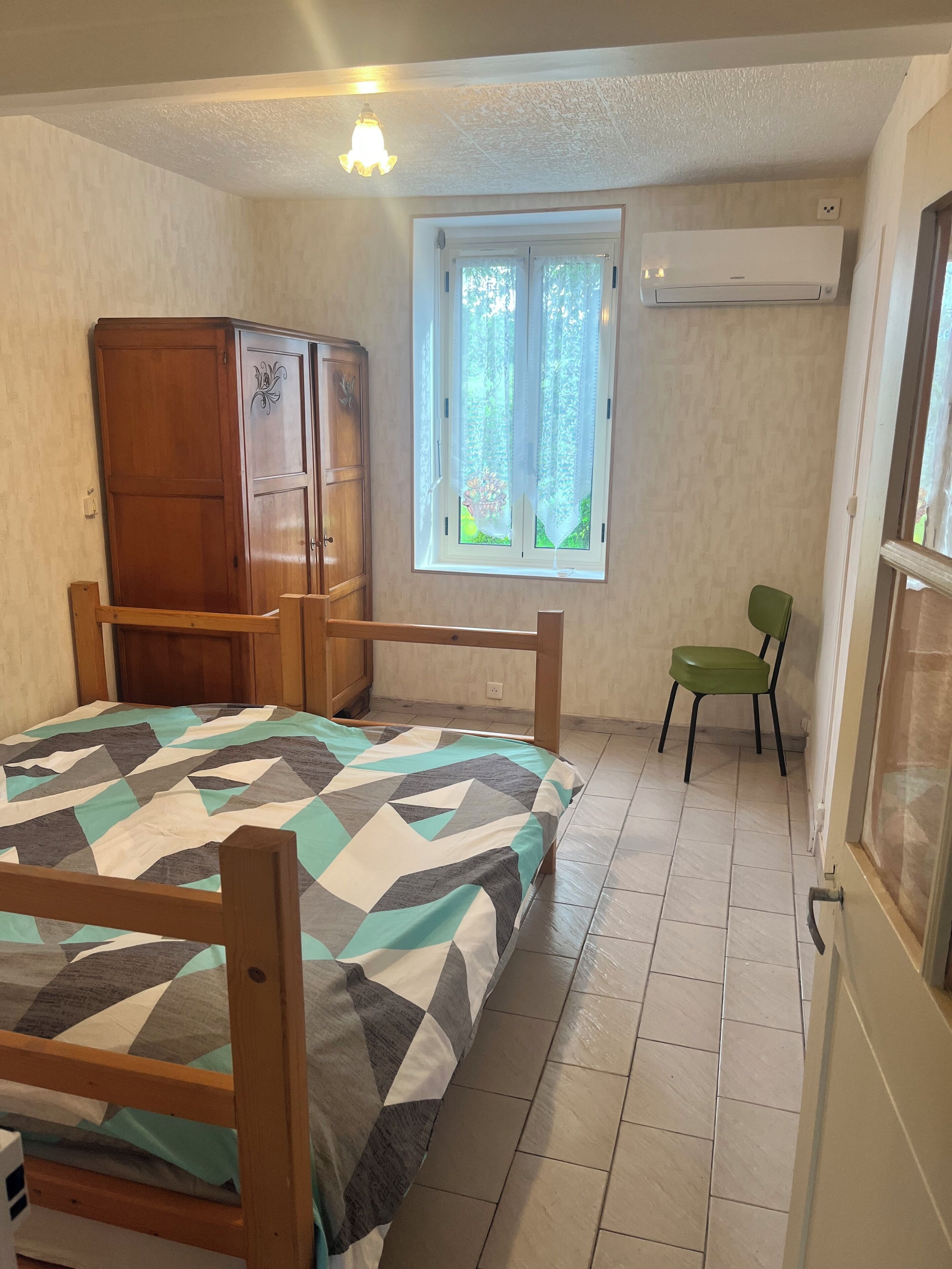 Une chambre à coucher avec un lit, une armoire, une fenêtre et une chaise.